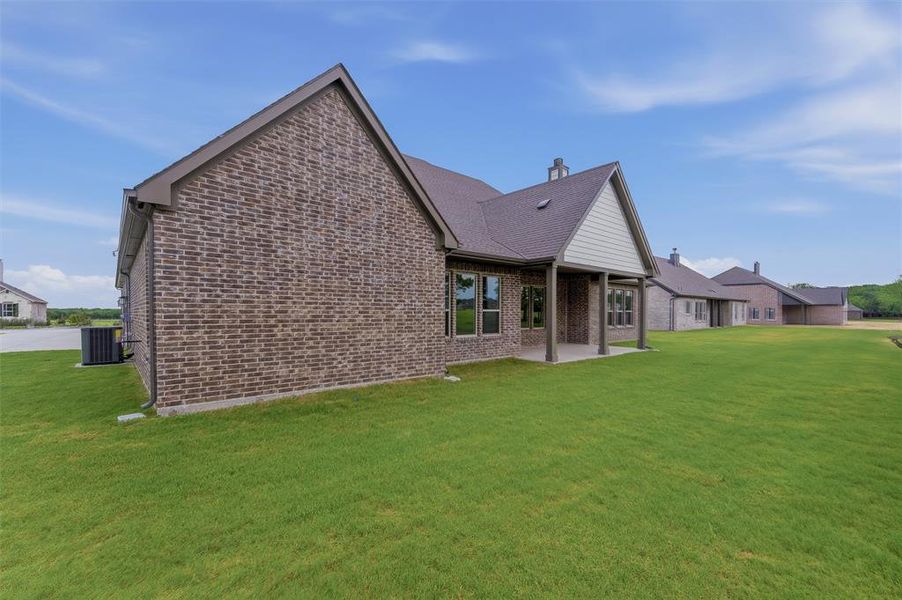 Expansive rear exterior featuring a covered patio, brick and siding facade, and multiple windows