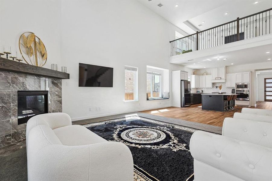 Living room with a towering ceiling, hardwood / wood-style flooring, and a tile fireplace