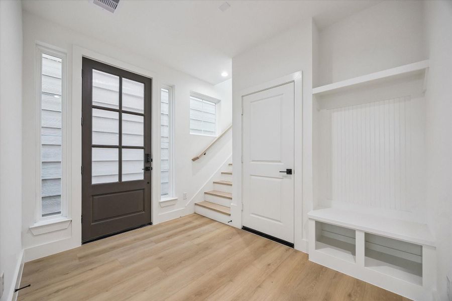 Welcoming entry with tall door, stair detail, and built-in drop zone