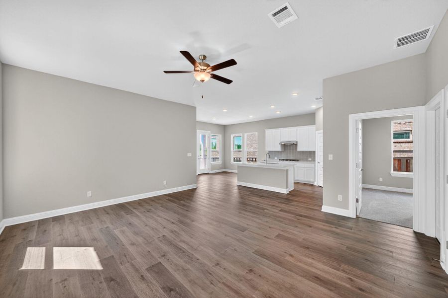 Unfurnished living room with dark wood-style flooring, ceiling fan, and recessed lighting Unfurnished living room with dark wood-style flooring, ceiling fan, and recessed lighting
