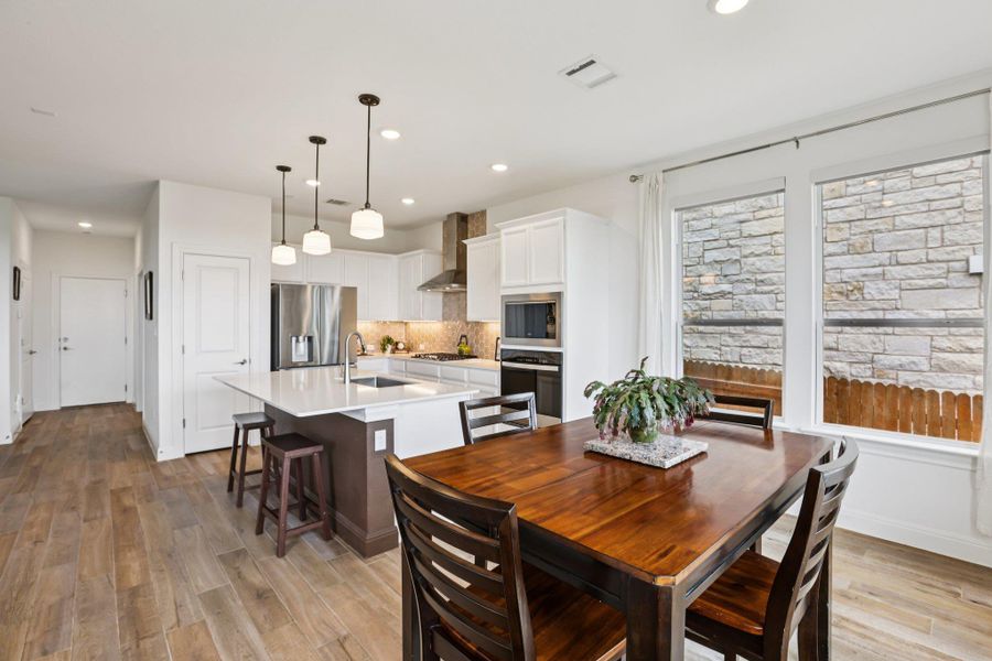 The kitchen features a center island with pendant lighting, stainless steel appliances, and white cabinetry