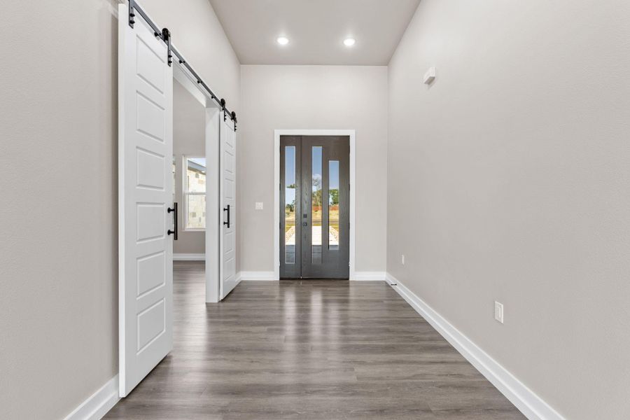 A spacious entry hall features high ceilings, sliding barn doors, and a modern glass-paneled entry door. A spacious entry hall features high ceilings, sliding barn doors, and a modern glass-paneled entry door.
