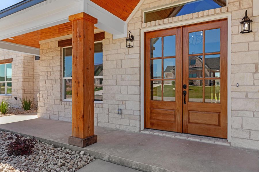 Property entrance with french doors, stone siding, and covered porch Property entrance with french doors, stone siding, and covered porch