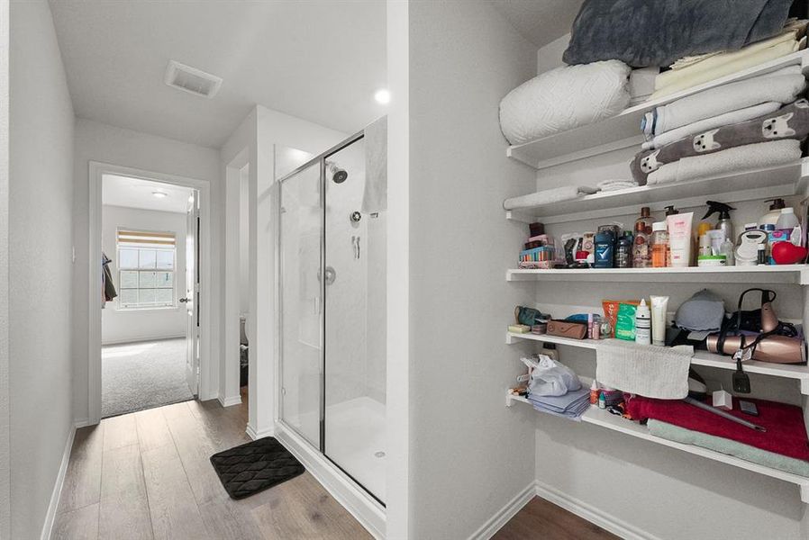 Full shower enclosure with a glass door, wall-mounted showerhead, and integrated shelving