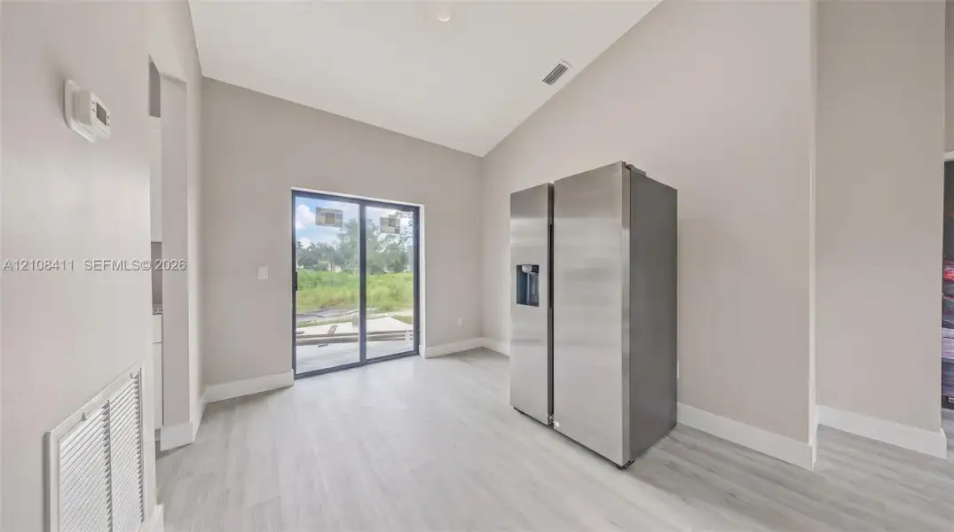 Vaulted ceilings, wood-finish flooring, and sliding glass doors providing natural light