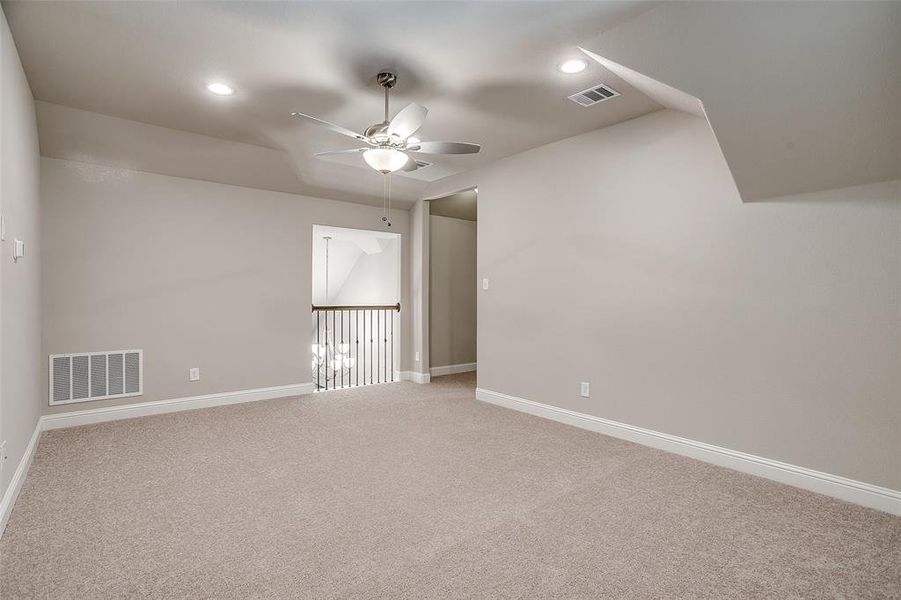 Carpeted empty room featuring vaulted ceiling and ceiling fan Carpeted empty room featuring vaulted ceiling and ceiling fan