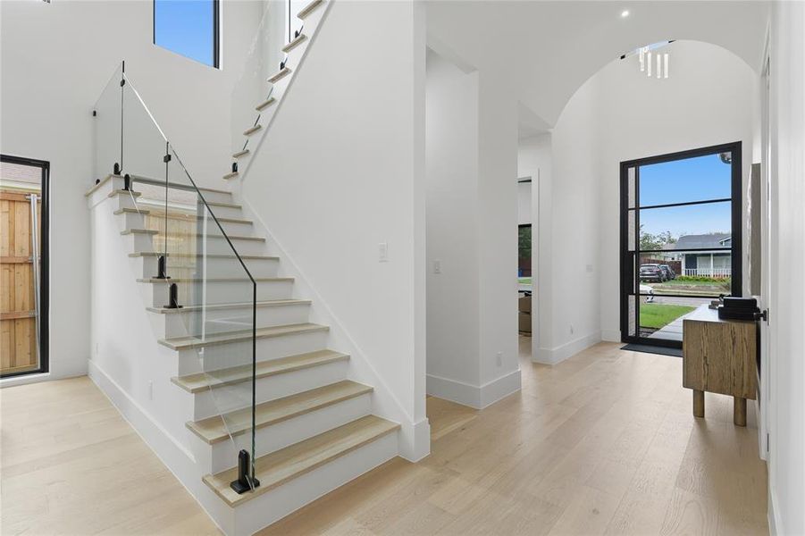Grand entryway featuring a contemporary staircase with glass railings and wood-finish treads Grand entryway featuring a contemporary staircase with glass railings and wood-finish treads