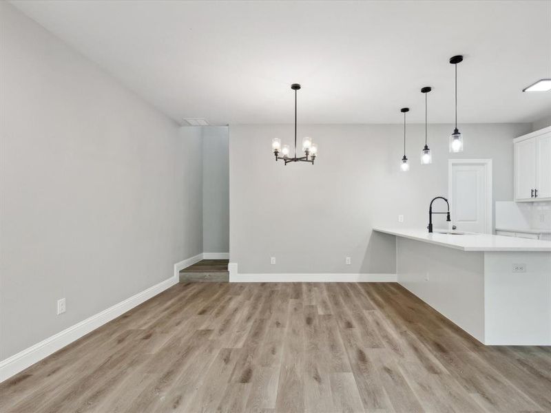 Unfurnished dining area with sink, hardwood / wood-style floors, and a chandelier