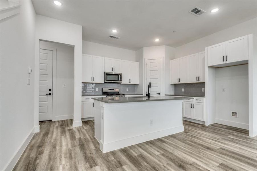 Kitchen featuring white cabinets, stainless steel appliances, and a kitchen island with sink