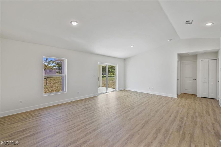 Spare room with vaulted ceiling, light wood-style floors, and recessed lighting