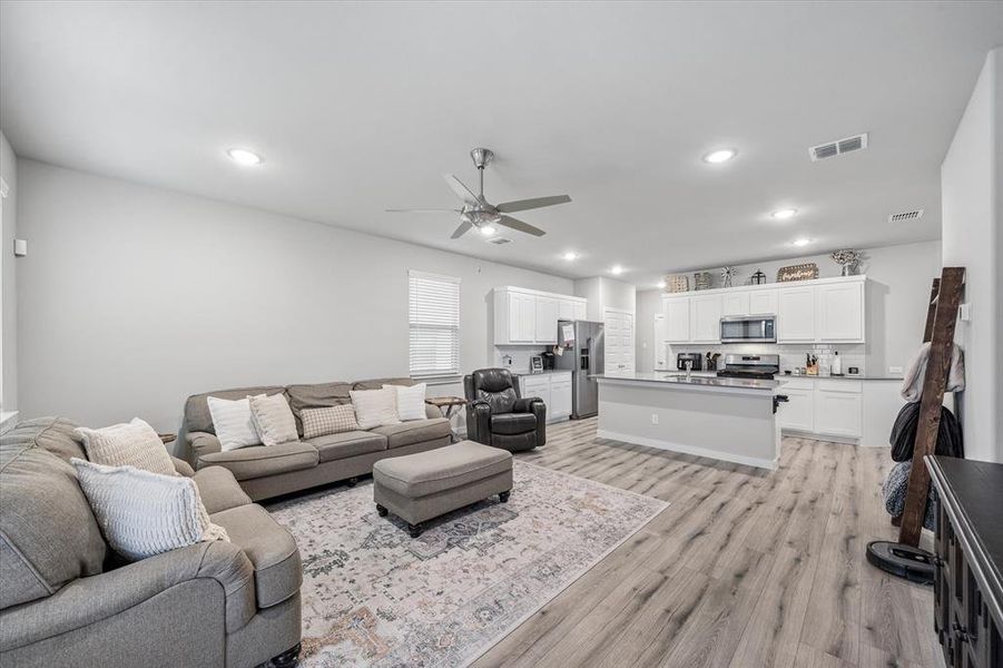 Living room with light hardwood / wood-style floors and ceiling fan