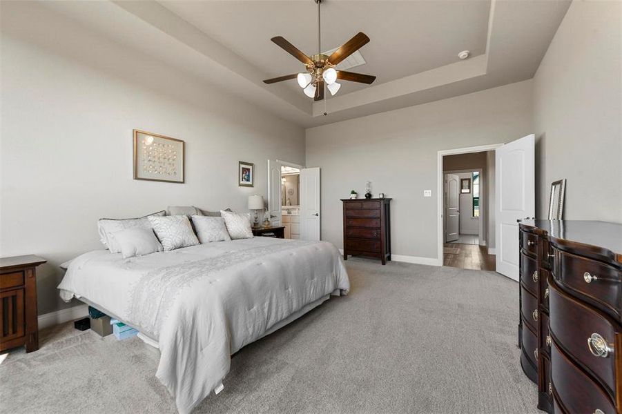 Carpeted bedroom with a tray ceiling, ceiling fan, and a towering ceiling