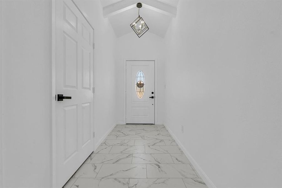 Doorway to outside featuring vaulted ceiling with beams and light tile patterned floors