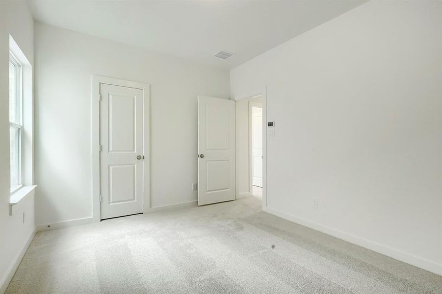 Carpeted room with white walls, a single window, and two paneled doors with chrome hardware