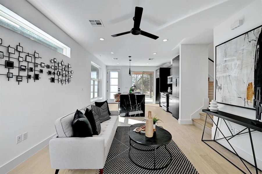 Living area with stairs, light wood-type flooring, a ceiling fan, baseboards, and recessed lighting