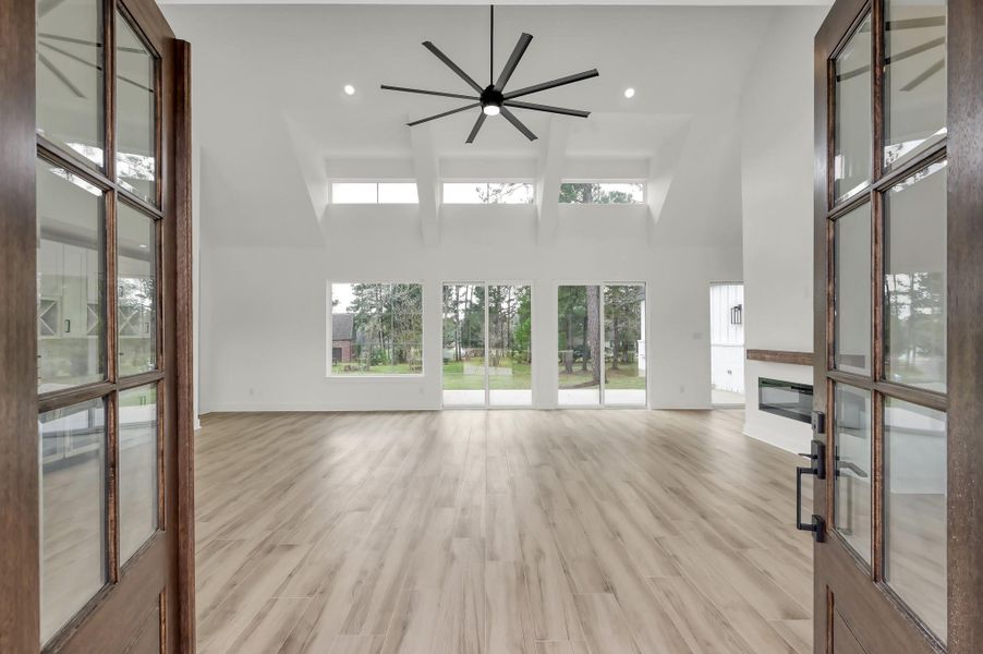 The impressive entry welcomes you into a spacious living area with cathedral ceilings, wood-look flooring, and abundant natural light.