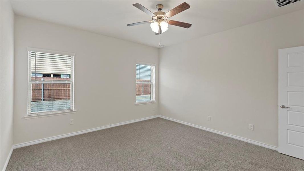 Carpeted interior room with white walls, two windows featuring horizontal blinds, and a ceiling fan with integrated lighting