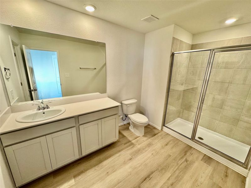 Full bathroom with a shower stall, vanity, and light wood-style floors