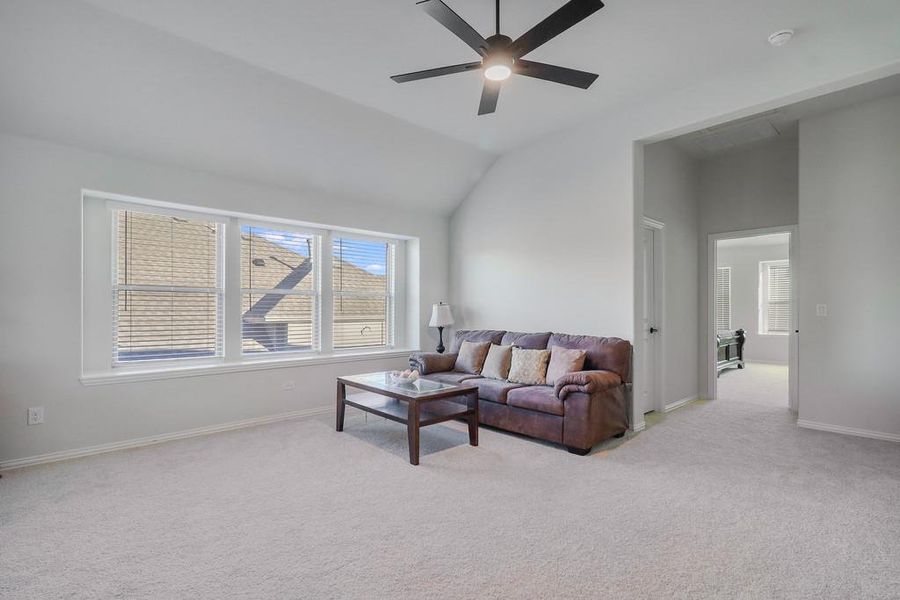Living room featuring light carpet, a ceiling fan, and lofted ceiling Living room featuring light carpet, a ceiling fan, and lofted ceiling