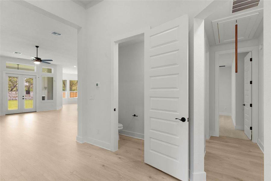 Hallway with attic access, light wood-style floors, and french doors Hallway with attic access, light wood-style floors, and french doors