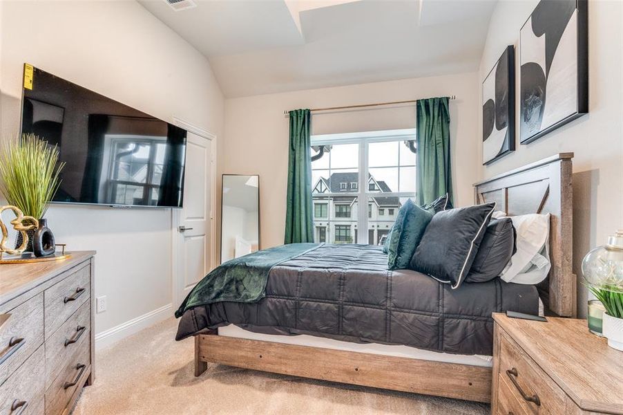 Bedroom featuring light carpet and vaulted ceiling