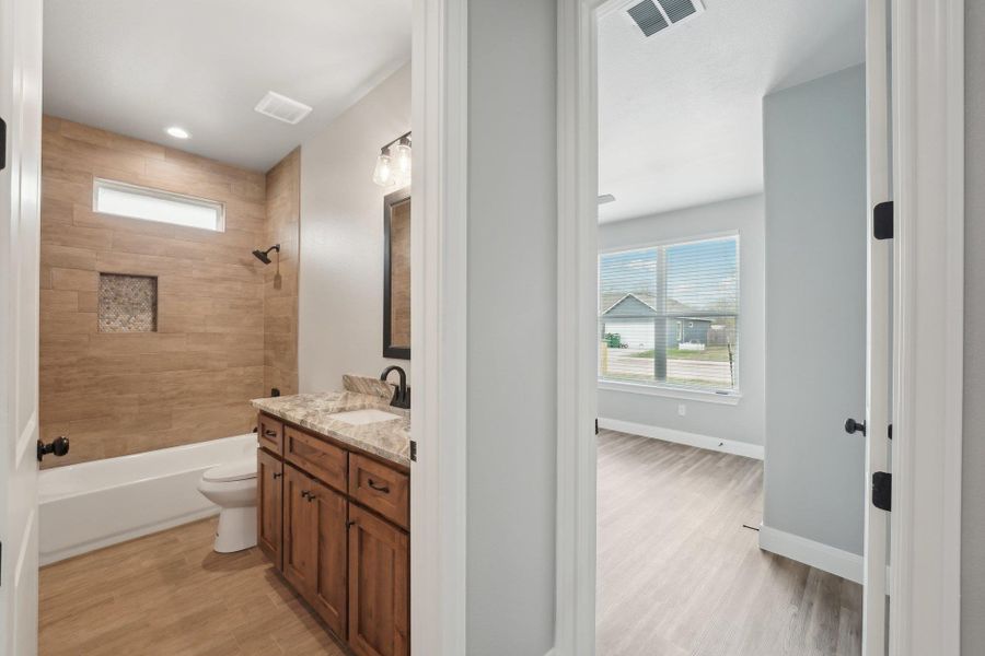 Bathroom featuring visible vents, toilet, wood finished floors, baseboards, and vanity