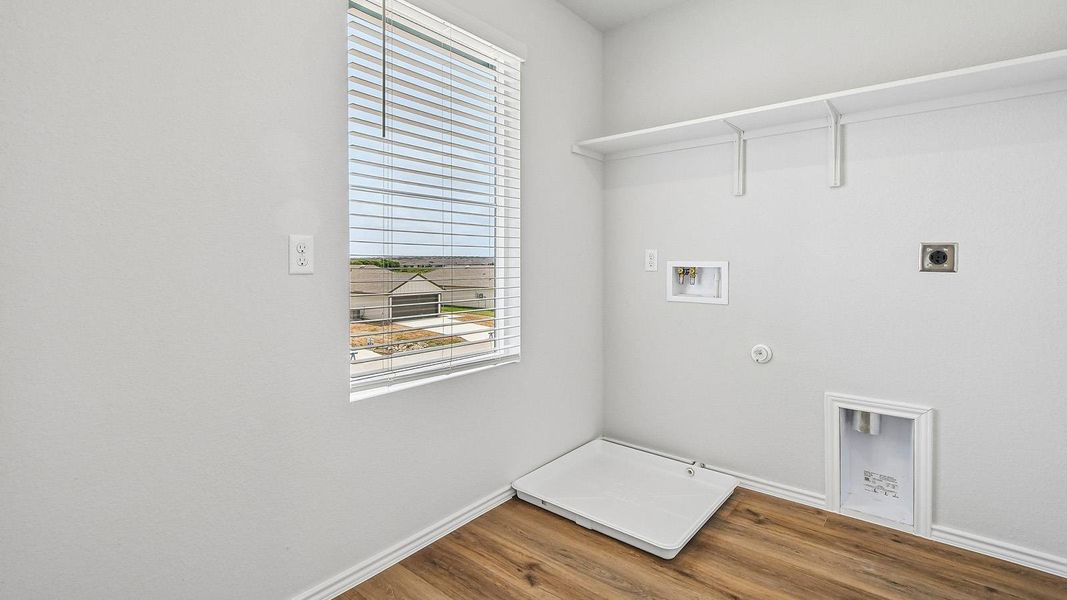 A well-appointed utility area featuring wood-look flooring and ample natural light for household tasks.