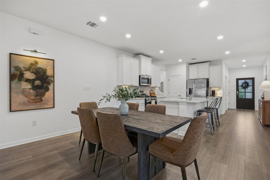 Open-concept dining area with wood-finish flooring, recessed lighting, and a dark wood-finish dining table