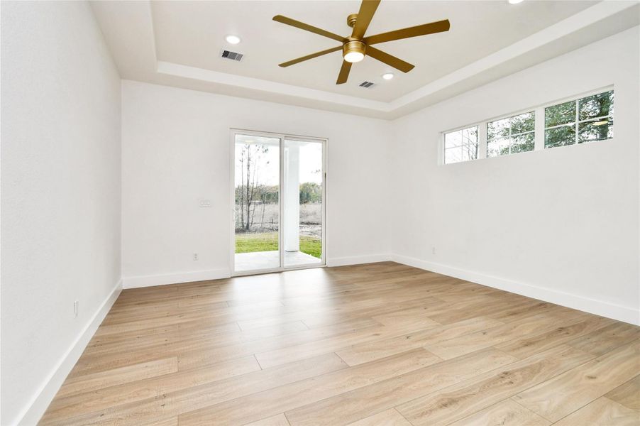 A sanctuary of comfort, this bedroom offers high tray ceilings and private access to the rear patio. Large windows and a neutral palette create a serene, restful environment.
