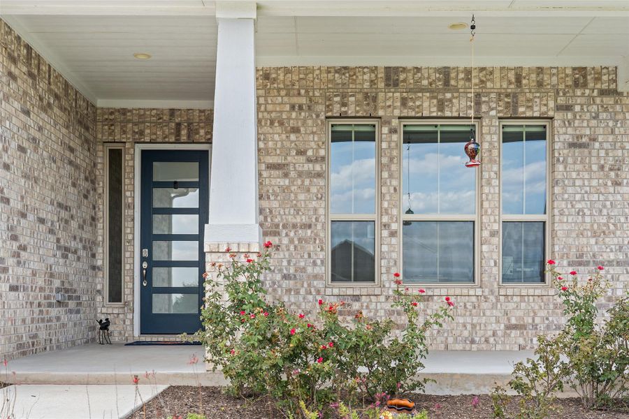 Entrance to property with brick siding and a porch
