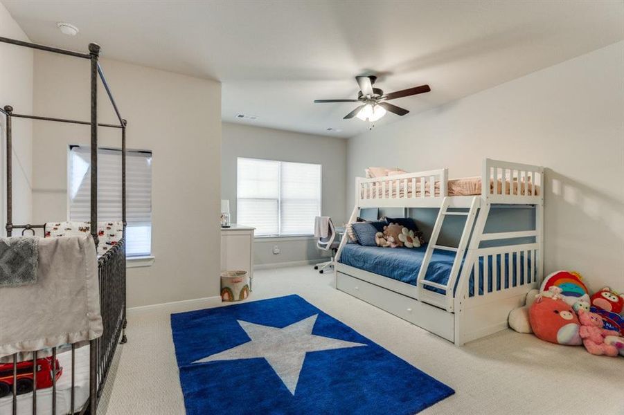 Carpeted bedroom with ceiling fan, visible vents, and baseboards