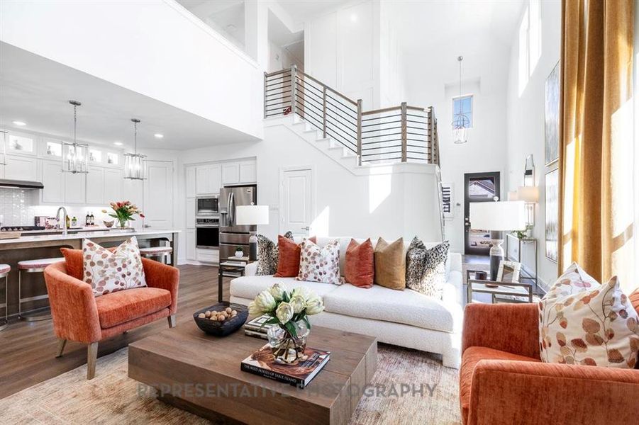 Living room with a chandelier, a towering ceiling, dark wood-type flooring, and stairway