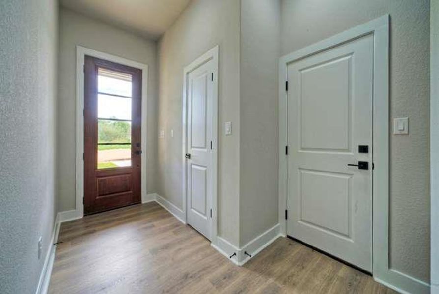 A welcoming entry features durable flooring and paneled interior doors, leading to a sun-lit exterior door.