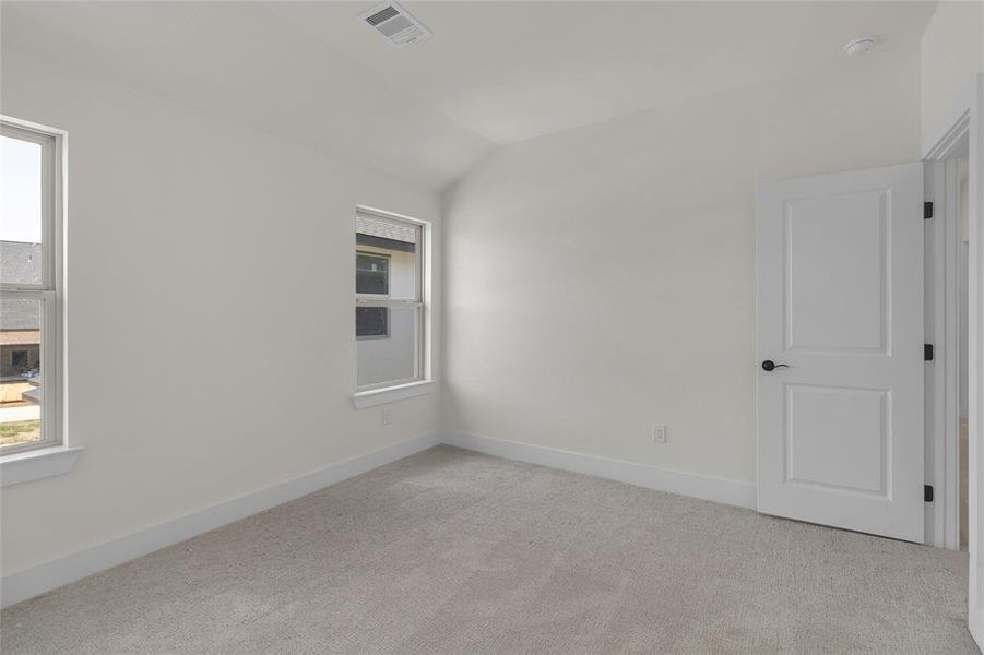 Carpeted room with vaulted ceilings and two windows