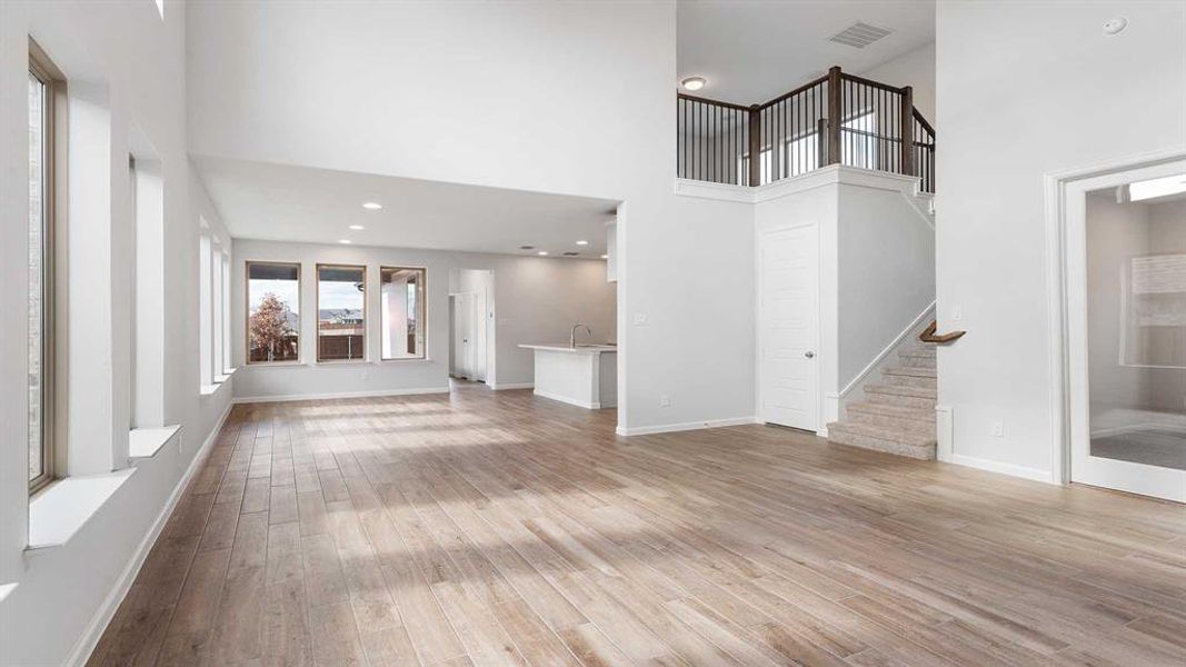 Unfurnished living room featuring light hardwood / wood-style flooring, sink, and a high ceiling