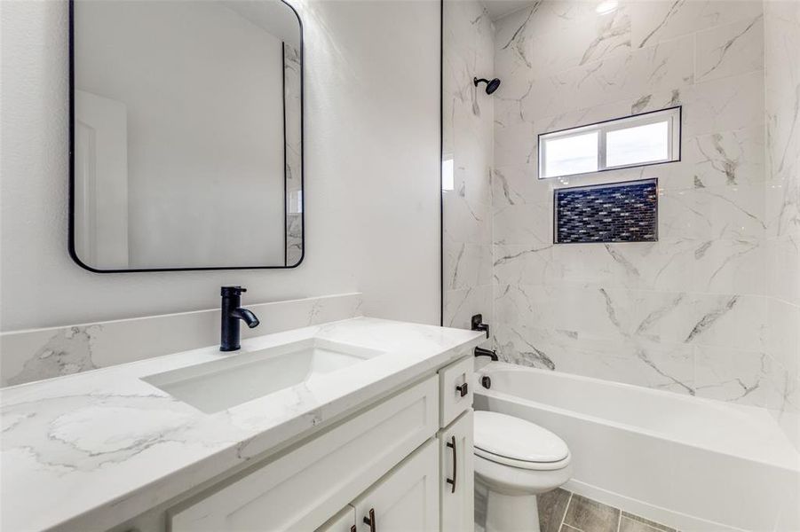 Full bathroom featuring tiled shower / bath combo, toilet, and vanity