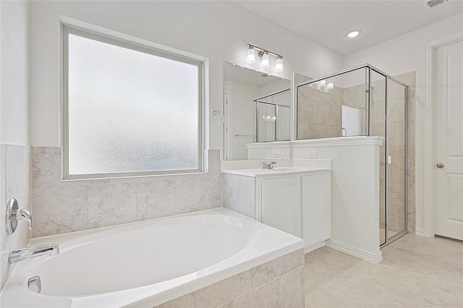Full bath with a shower stall, vanity, and a garden tub