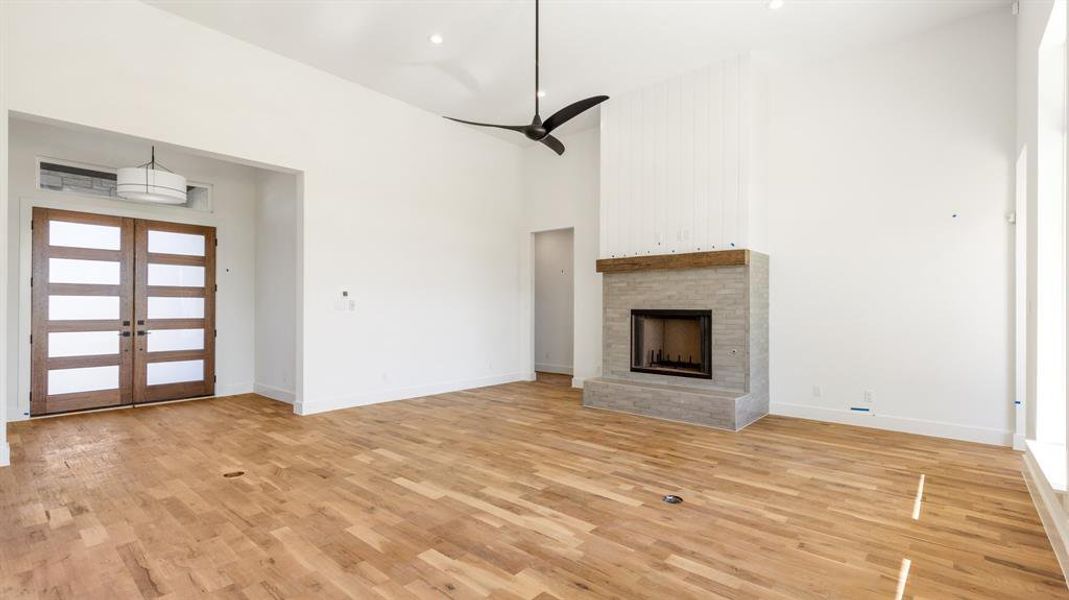 Unfurnished living room with ceiling fan, light hardwood / wood-style flooring, high vaulted ceiling, and french doors