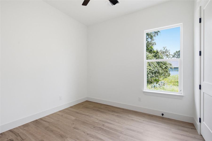 A well-lit room showcases modern laminate flooring and a refreshing outdoor green view. A well-lit room showcases modern laminate flooring and a refreshing outdoor green view.