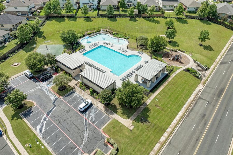 An aerial perspective reveals a vibrant community with recreational amenities including a swimming pool and expansive green spaces.