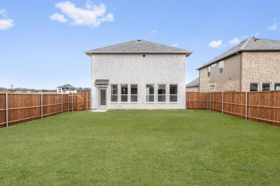 Rear view of property with a yard, a shingled roof, and a fenced backyard