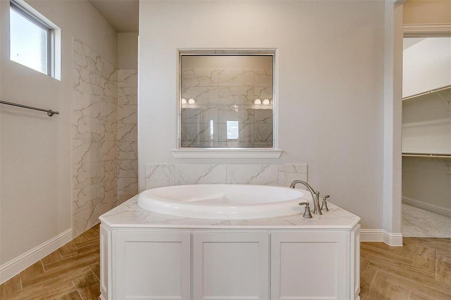 Bathroom featuring parquet floors and a bathing tub