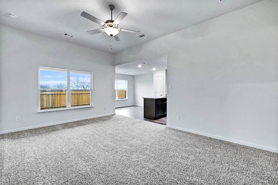 Unfurnished living room with carpet and ceiling fan