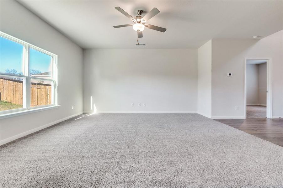 Spare room featuring a ceiling fan and dark carpet