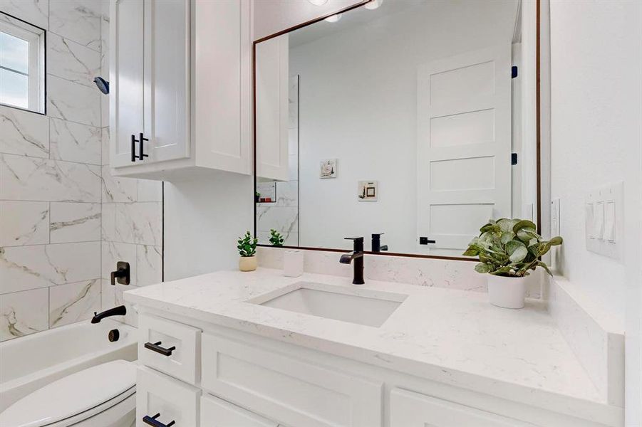 Full bathroom featuring tiled shower / bath combo, toilet, and vanity