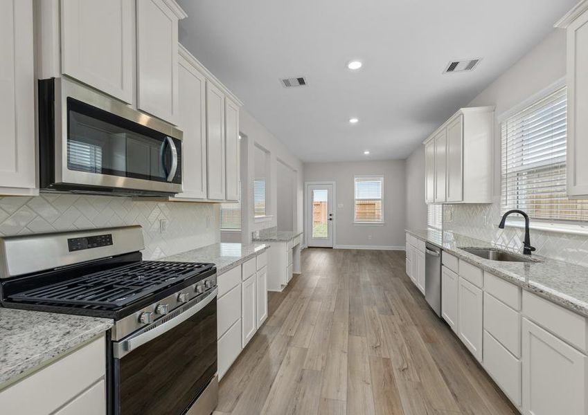 The kitchen has white cabinets and stainless steel appliances.