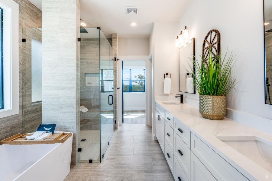 Bathroom with double vanity, a shower stall, a freestanding tub, and recessed lighting