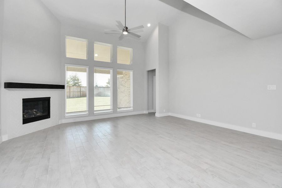 Welcome family and guests to your charming living room! With its high ceilings, recessed lighting, ceiling fan, custom paint, beautiful flooring, and large windows that let in abundant natural light, this room is perfect for gatherings. Sample photo of completed home with similar floor plan. Actual colors and selections may vary.