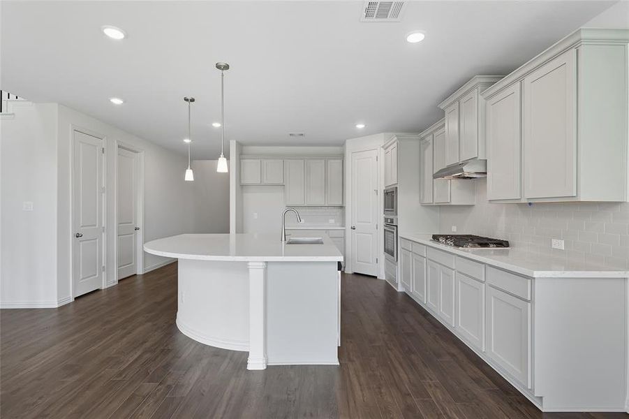 Kitchen featuring tasteful backsplash, decorative light fixtures, a kitchen island with sink, recessed lighting, and dark wood-style floors Kitchen featuring tasteful backsplash, decorative light fixtures, a kitchen island with sink, recessed lighting, and dark wood-style floors