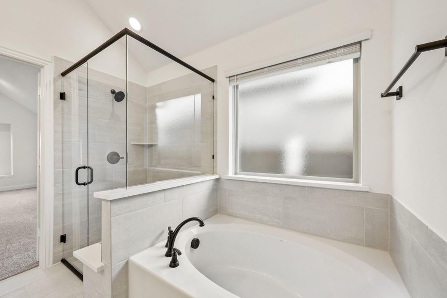 Bathroom with soaking tub, glass-enclosed shower, gray tile walls, and black fixtures Bathroom with soaking tub, glass-enclosed shower, gray tile walls, and black fixtures